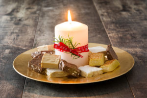 Christmas nougat and white candle on a golden plate