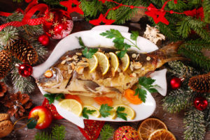 roasted whole carp stuffed with vegetables and almonds on wooden table for christmas-top view